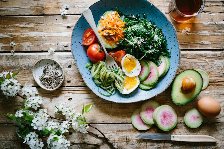 Plate with eggs, fresh salad and sliced avocado