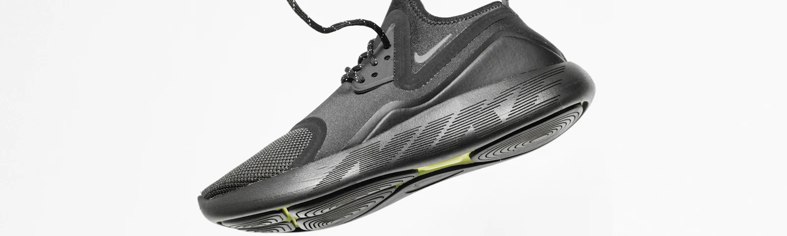 Black running shoe suspended against a white background