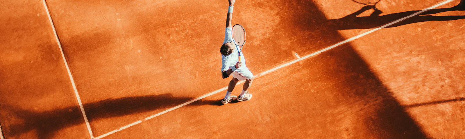 Aerial view of an orange clay tennis court with white lines