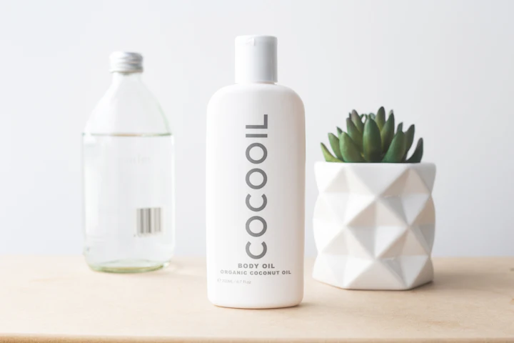 Glass bottle of coconut oil beside a small succulent plant