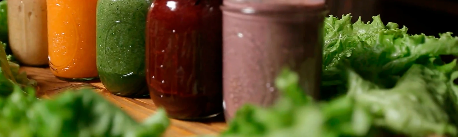 A row of colorful fruit and vegetable smoothies in glasses