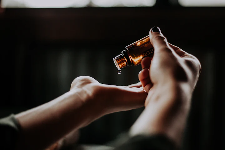 A glass dropper releasing a drop of facial oil onto an open hand