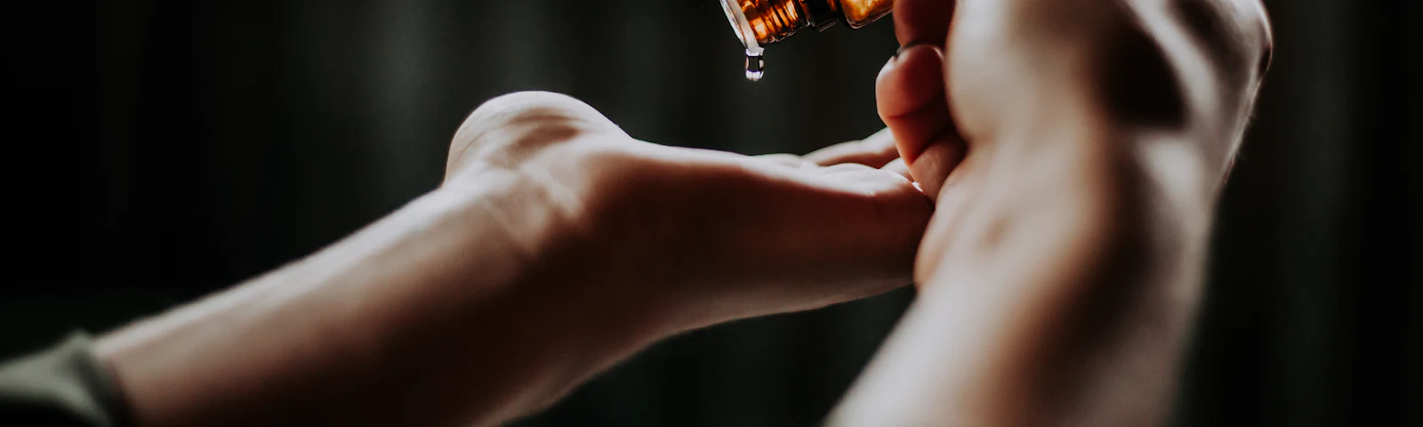 A glass dropper releasing a drop of facial oil onto an open hand