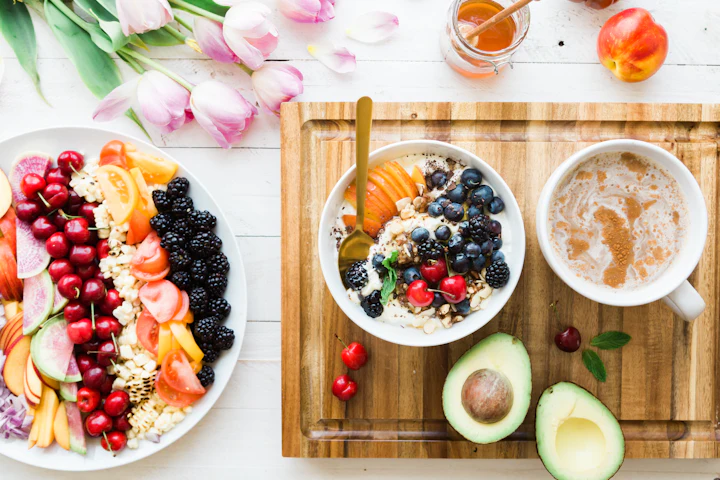 Breakfast spread with fresh fruit, a bowl of oatmeal and sliced avocado on a table