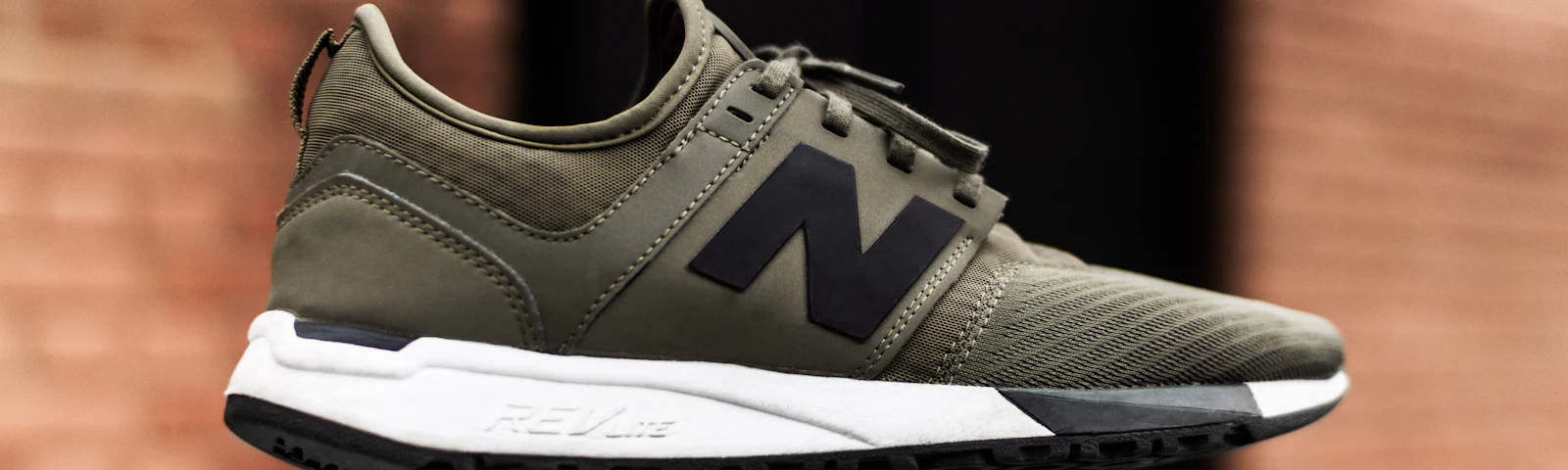 Olive green New Balance sneaker on a plain background