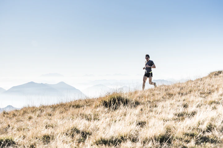 Person walking briskly up a grassy hill outdoors