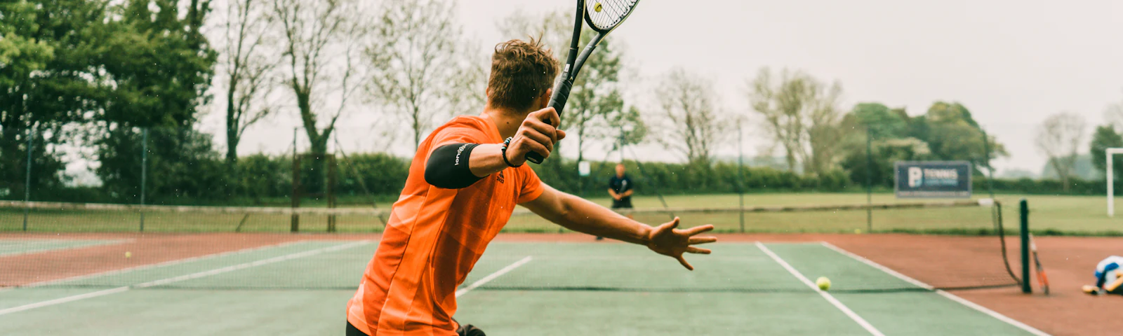 Man hitting a forehand on a grass tennis court
