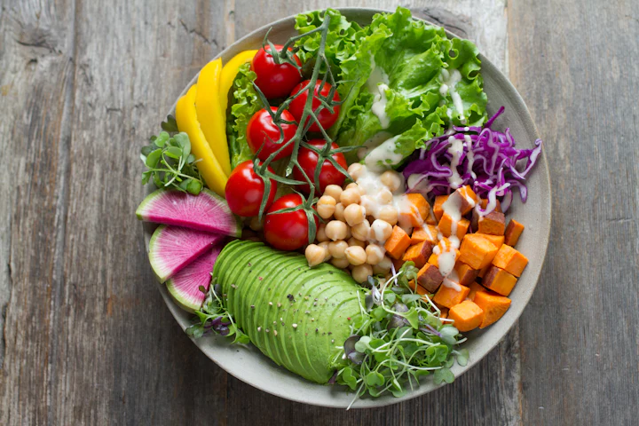 Colorful vegan bowl with greens, vegetables, grains and seeds