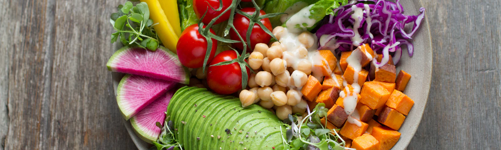 Colorful vegan bowl with greens, vegetables, grains and seeds